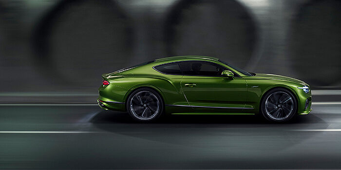  Bentley Bristol Bentley Continental GT coupe in Tourmaline Green paint driving in profile on a dark road