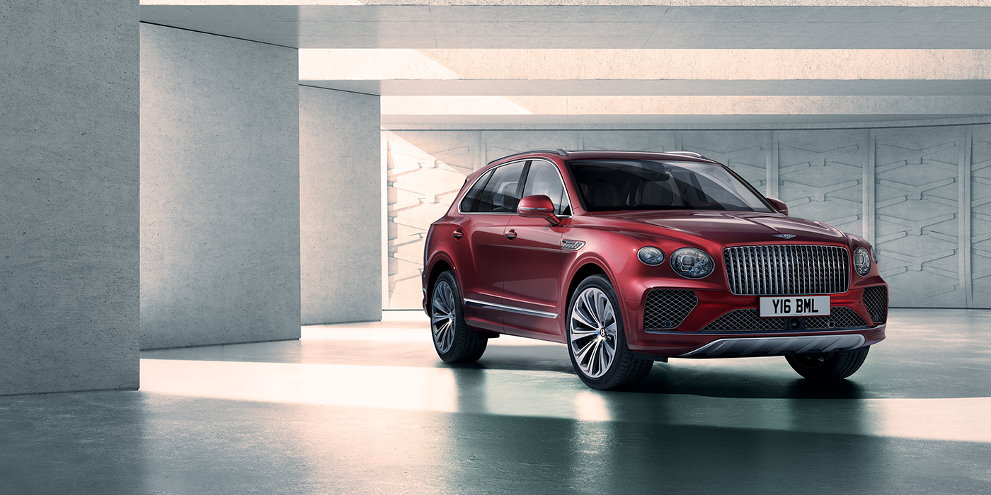 Bentley Bristol Bentley Bentayga Atelier Edition SUV in Rubino Red paint front three quarter against textured concrete wall