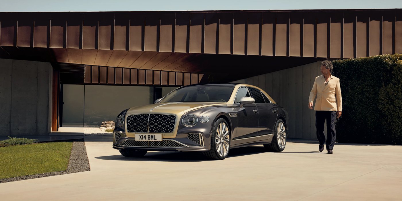 Bentley Bristol Bentley New Flying Spur Mulliner V8 hybrid sedan front three quarters in Rose Gold over Magnetic paint, parked near modern home