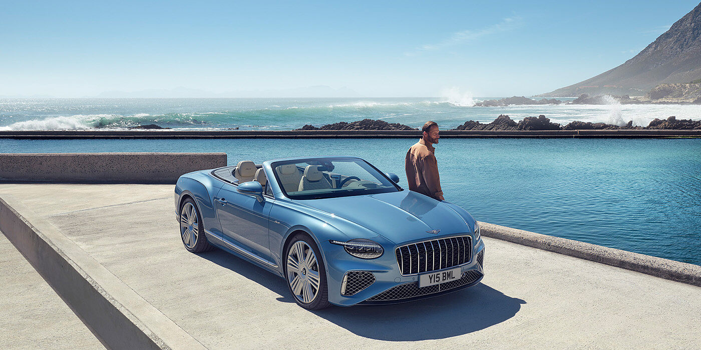 Bentley Bristol New Bentley Continental GTC Azure convertible front view in Light Windsor blue paint with 22 inch ten spoke wheels parked by the sea in the sunshine