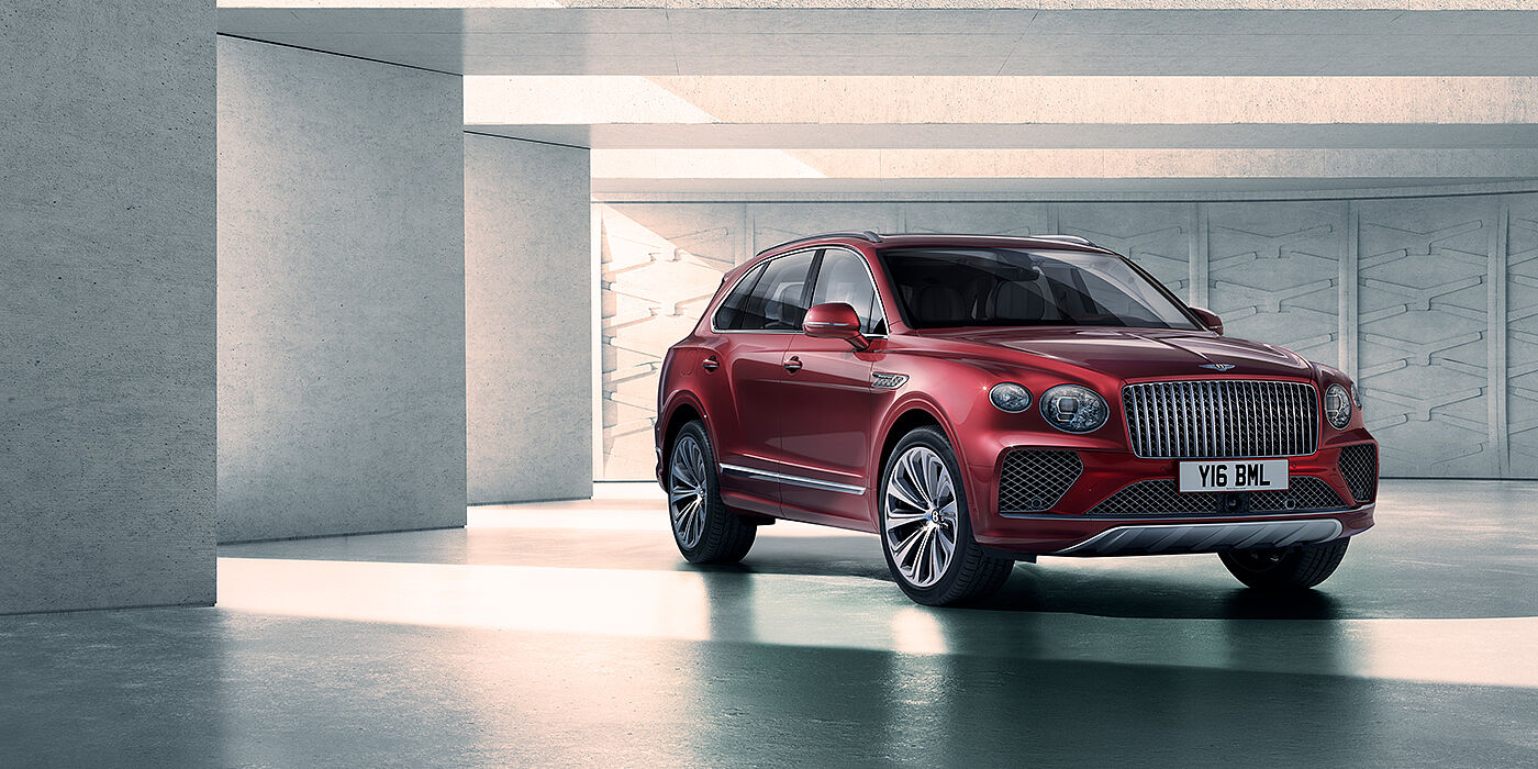 Bentley Bristol Bentley Bentayga Atelier Edition SUV in Rubino Red paint front three quarter against textured concrete wall