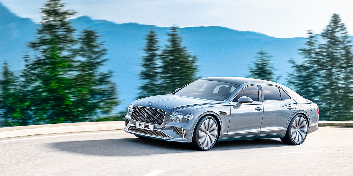 Bentley Bristol New Bentley Flying Spur sedan side view in Silverlake paint with ten spoke wheels and chrome matrix grille driving dynamically on a mountain road