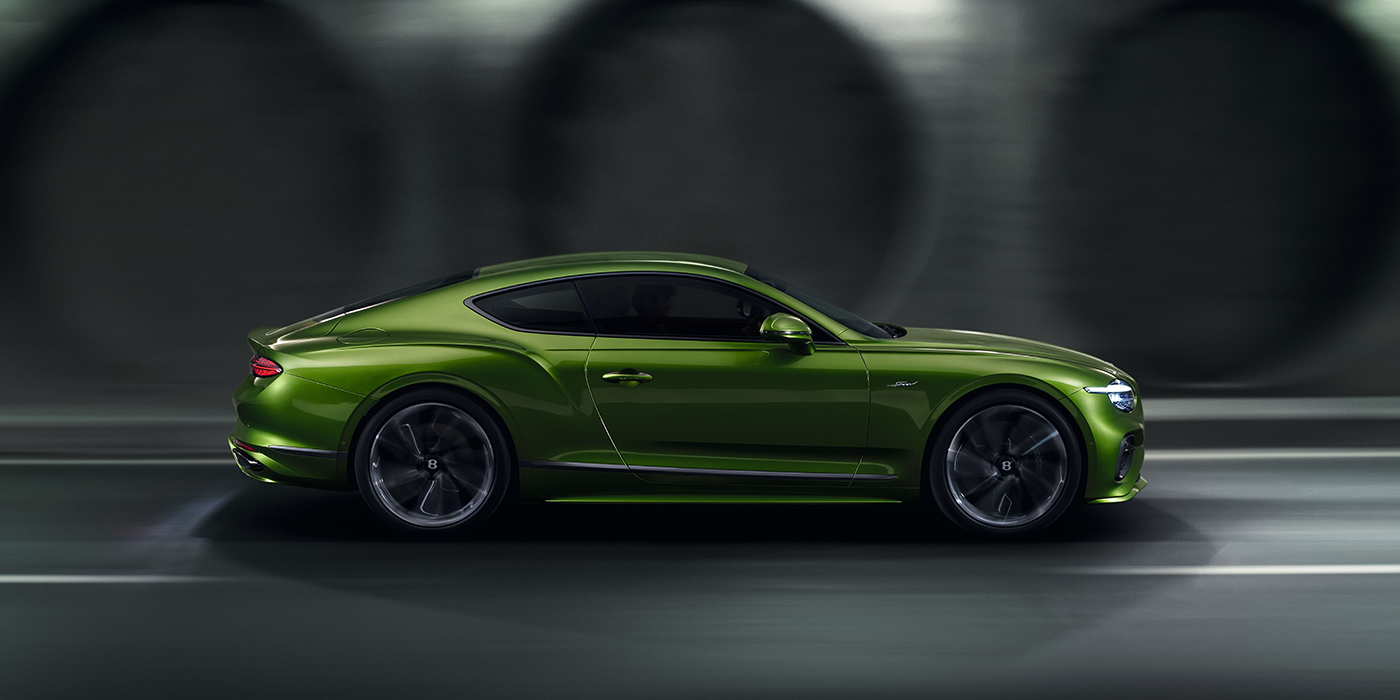 Bentley Bristol Bentley Continental GT coupe in Tourmaline Green paint driving in profile on a dark road